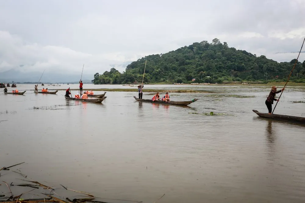 Tourists sit on a dugout canoe enjoying the serene beauty of Lake Lắk