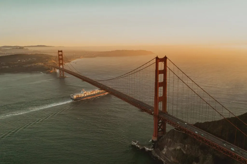Golden Gate Bridge sparkling at night, with bright yellow lights against a dark blue sky.