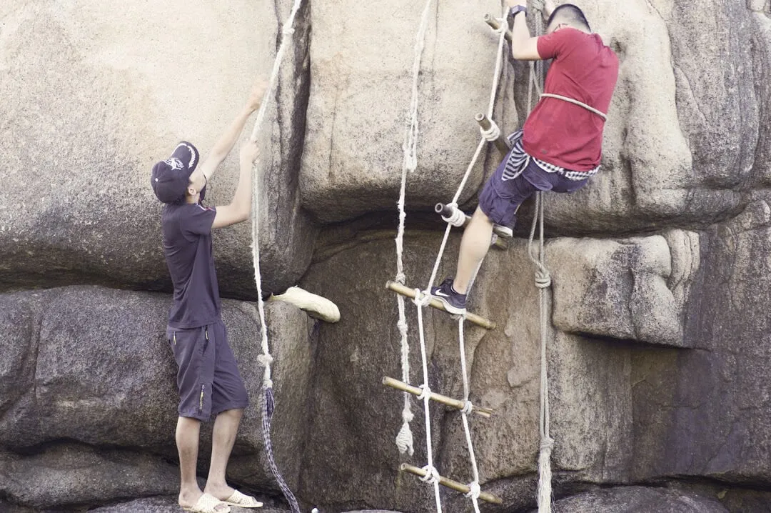 Group using ropes to climb over dangerous rocky cliffs to reach Mui Doi