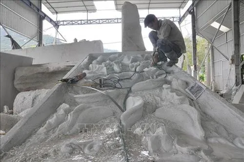 Stone carvers in Chuong Village, Tan Linh Commune, crafting a white stone relief.