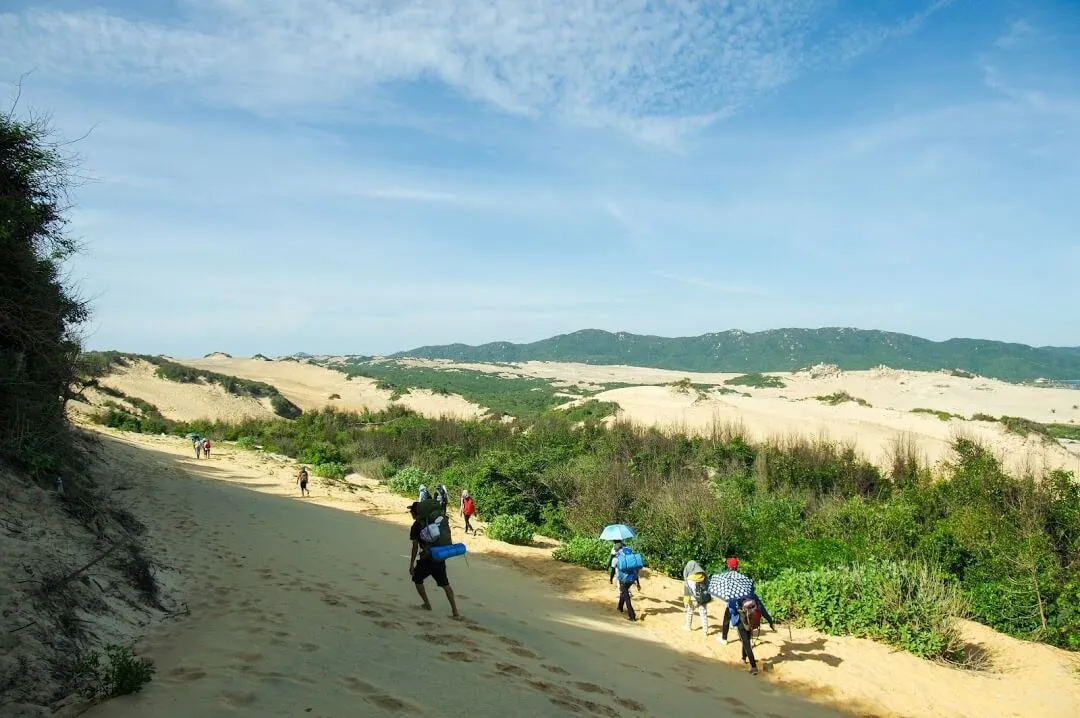 Trekking group crossing white sand dunes in the journey to conquer Mui Doi