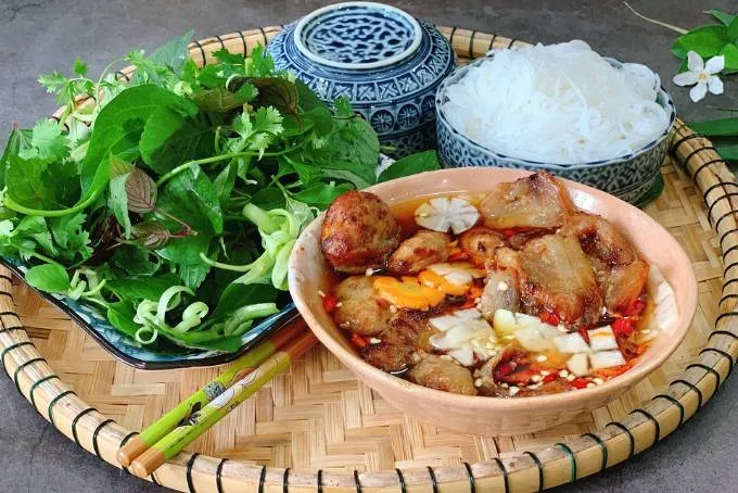 The standard way to eat Hanoi bun cha by dipping vermicelli and grilled pork separately into the dipping sauce
