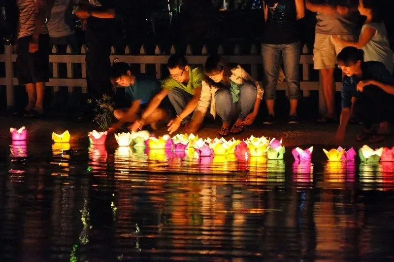 People releasing flower lanterns from a boat on the Hoai River.