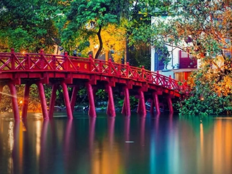 Cầu Thê Húc dẫn vào đền Ngọc Sơn, Hà Nội, với màu sơn đỏ son nổi bật trên mặt hồ xanh.