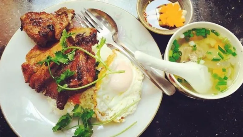 A close-up of a large, flavorful grilled pork chop at Cơm Tấm Nguyễn Văn Cừ in Saigon, showcasing the restaurant's signature dish.