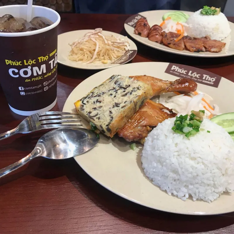 A variety of dishes at Cơm Tấm Phúc Lộc Thọ, a Saigon broken rice chain known for its diverse menu and delivery service, showcasing different toppings and side dishes.