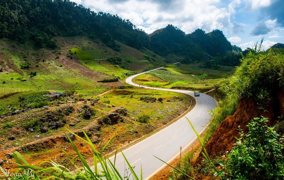 The S-shaped road curves through canola flower fields in Moc Chau.
