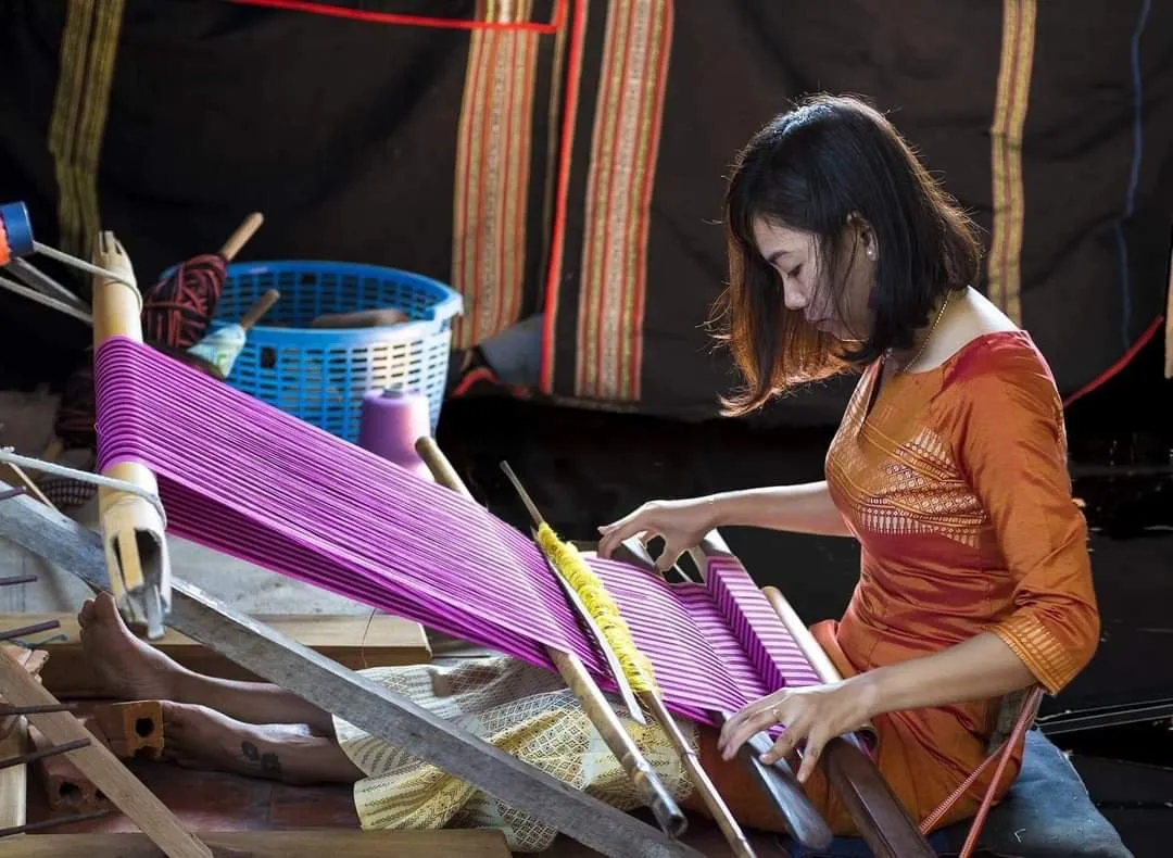 Close-up of a Cham woman weaving intricate patterns on a traditional loom in My Nghiep village.