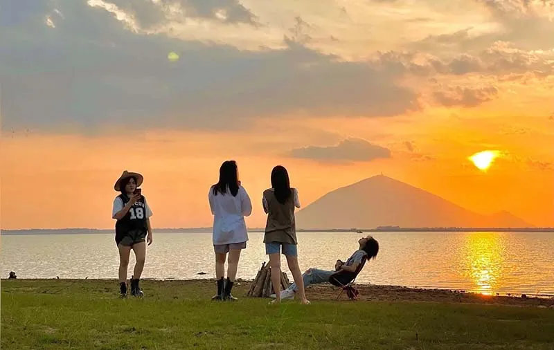 Visitors watching a romantic sunset by Dau Tieng Lake