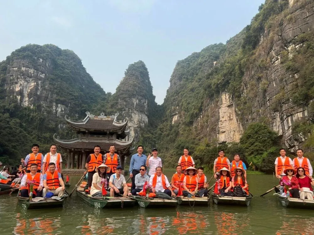 Tourists enjoying a boat tour in Trang An, Ninh Binh, a UNESCO World Heritage site with stunning karst landscapes.