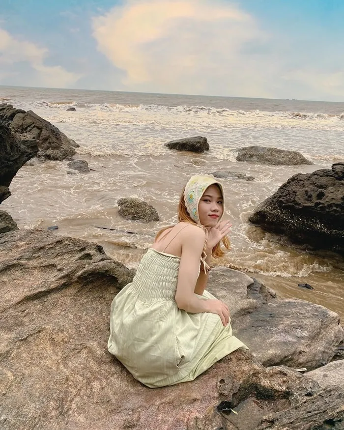 Tourists relaxing on the rocks at Hon Bo, admiring the vast ocean and enjoying the fresh air