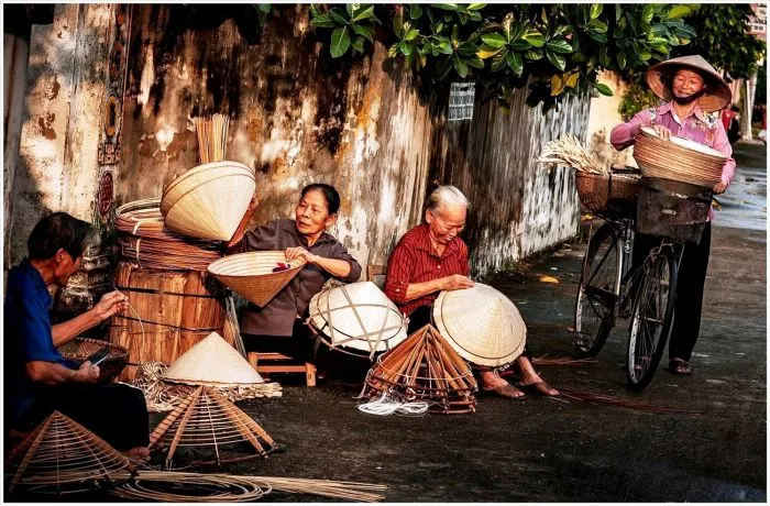 Du khách trải nghiệm làm nón tại làng Phú Cam.