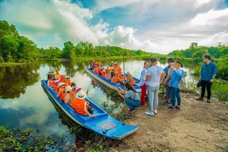 Du khách trải nghiệm tour tham quan rừng tràm Làng nổi Tân Lập bằng xuồng ba lá trong trang phục áo bà ba truyền thống