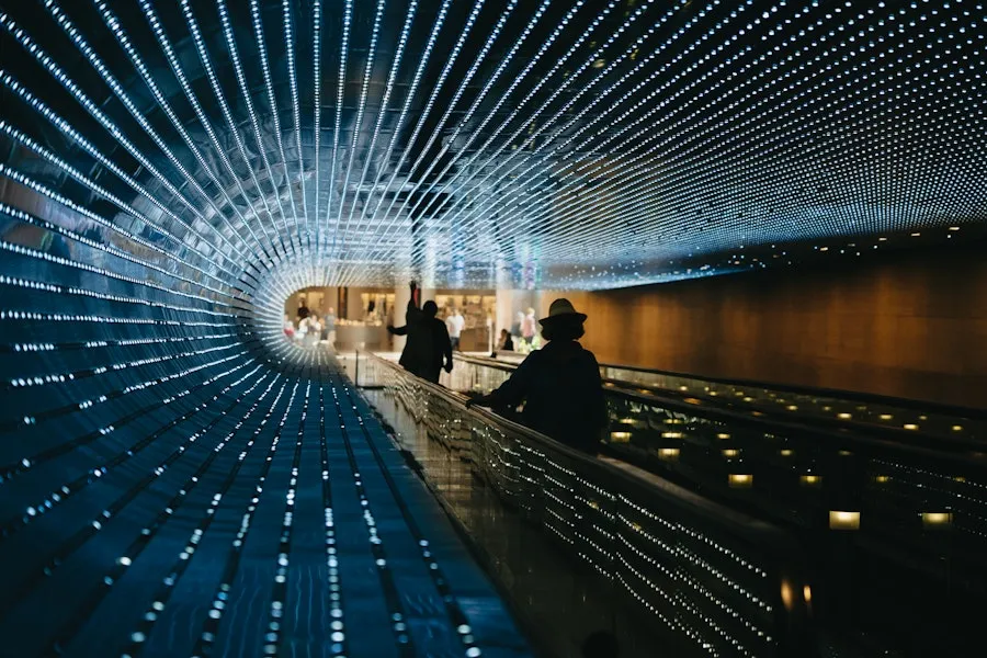 Pedestrian tunnel illuminated with vibrant light displays, creating a dynamic and futuristic experience as visitors pass through.
