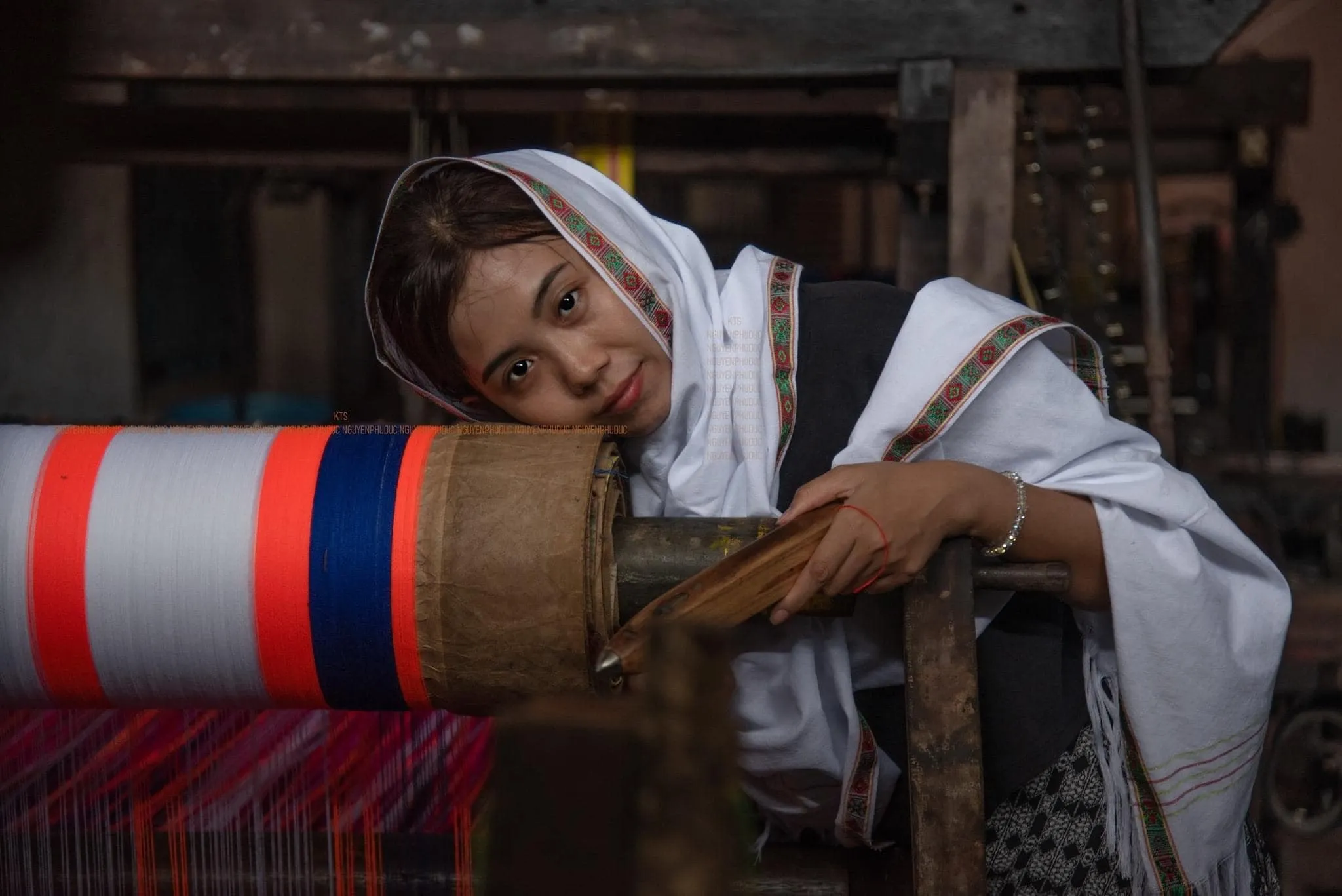 A tourist trying traditional Cham weaving at a loom in My Nghiep village, guided by a local artisan.