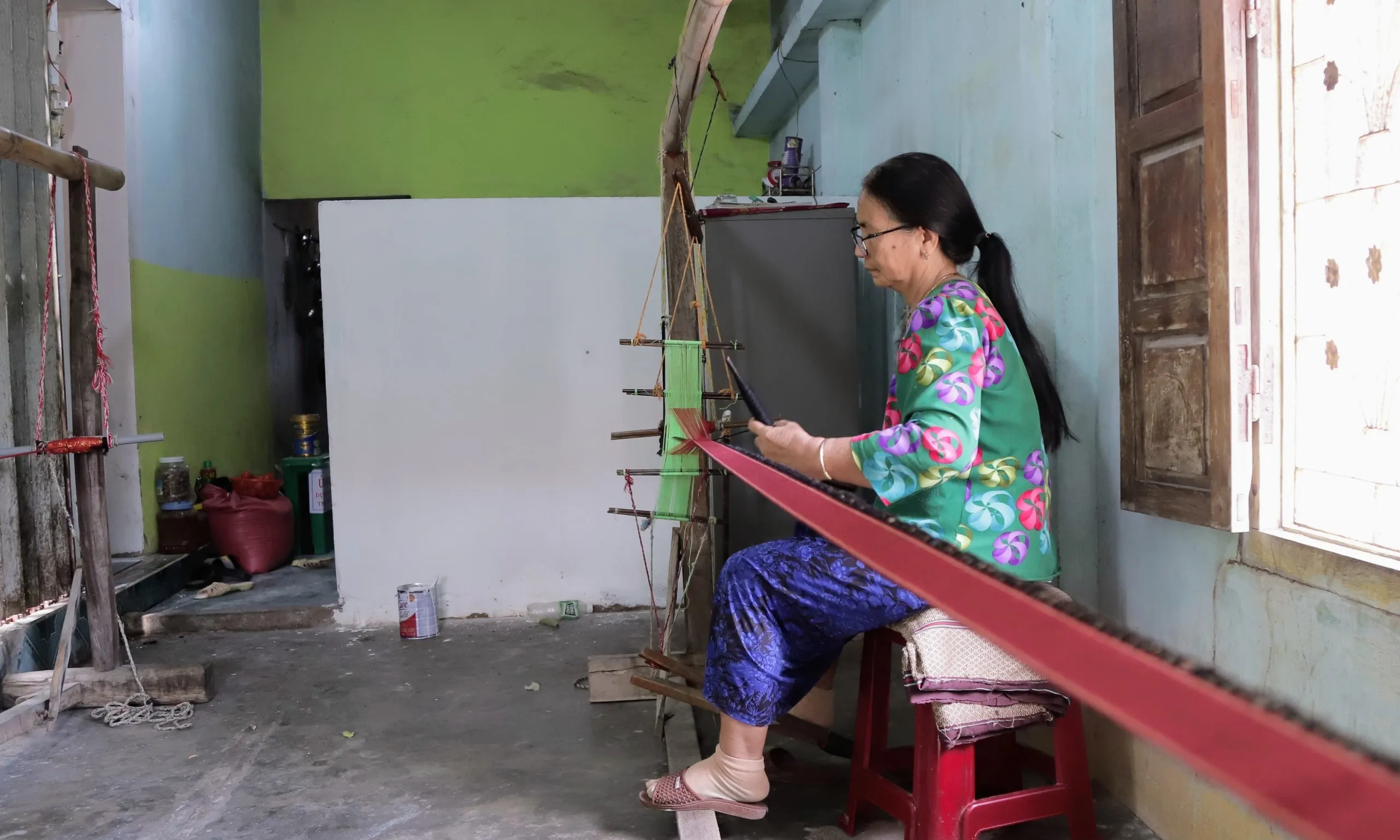 A collection of colorful Cham brocade fabrics showcasing diverse patterns and textures in a workshop.