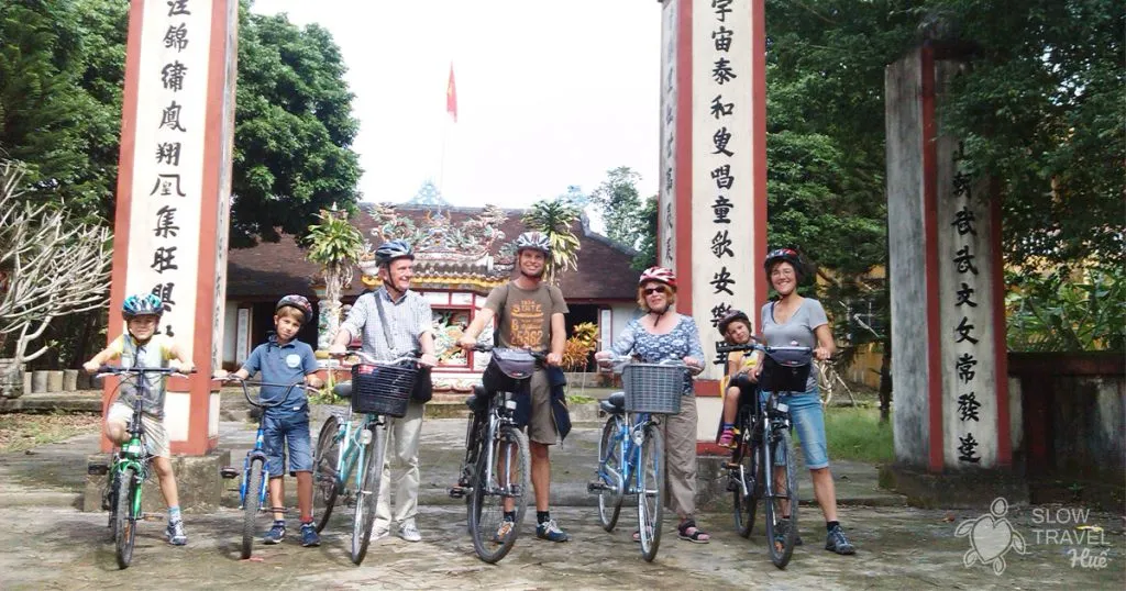 Family and bicycles in front of an ancient village communal house