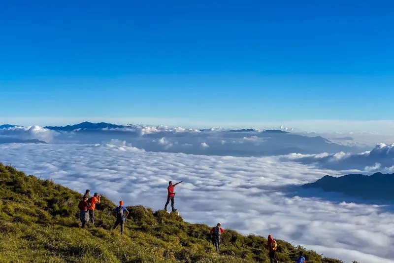 A hiker standing on a mountain ridge in Lung Cung surrounded by clouds