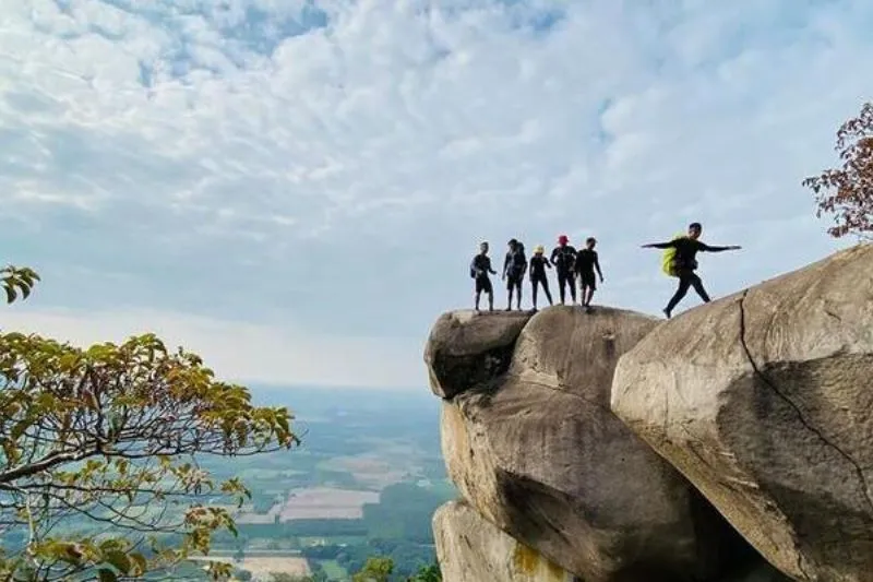 Hikers climbing stone steps on Ba Den Mountain surrounded by lush vegetation