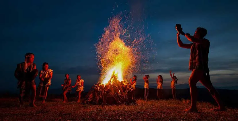 Villagers walking around a flickering fire