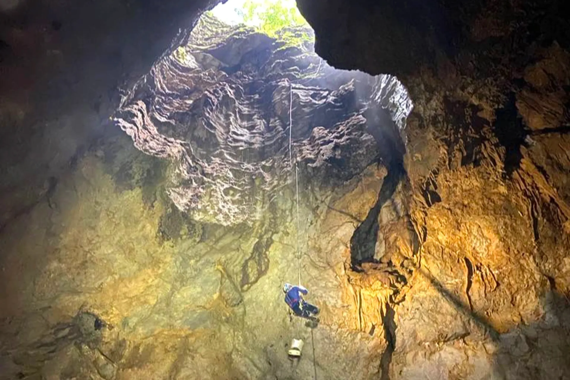 A member of the expedition team exploring a newly discovered cave, highlighting its scale and magnificence