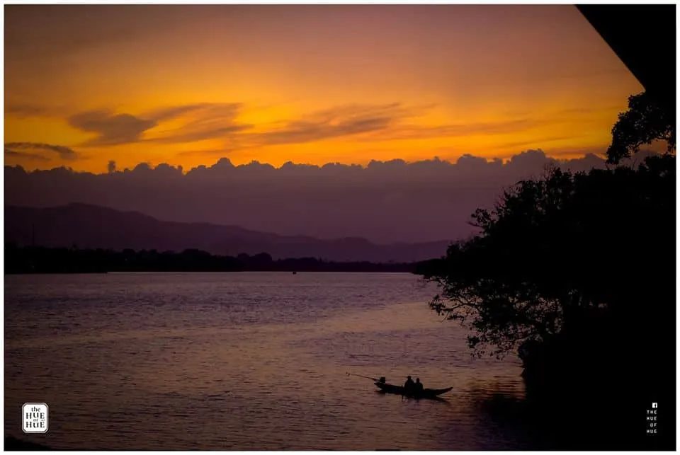 Purple sunset on the Perfume River, reflecting twilight on the peaceful river and ancient architectural structures.