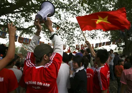 Spectators enthusiastically cheer for the boat racing teams on the Nhuệ River