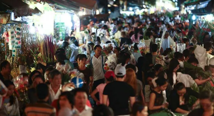 A bustling and vibrant scene at Ho Thi Ky Flower Market during nighttime.