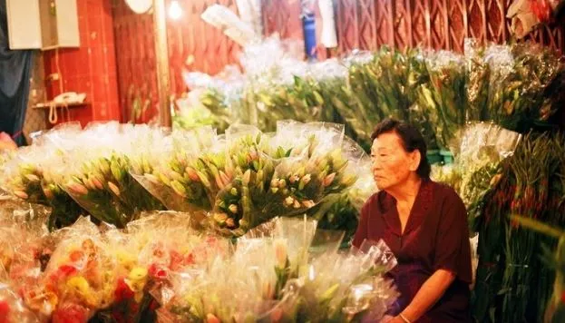 A friendly flower vendor arranging bouquets at Ho Thi Ky Flower Market.