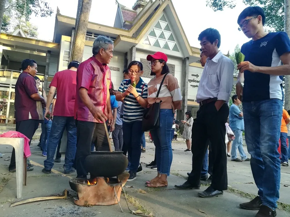 Ông Thanh Sang đang rang nếp trong nồi đất, giới thiệu cách làm cốm dẹp cho du khách tại Bảo tàng Văn hóa Dân tộc Khmer