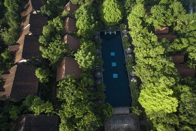 A tranquil scene at Pilgrimage Village Boutique Resort & Spa showcasing traditional Vietnamese architecture with wooden houses and lush gardens, evoking a local and peaceful atmosphere.