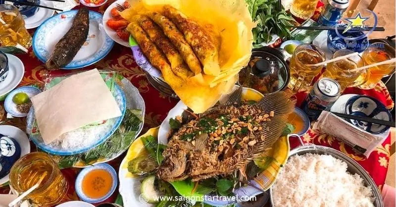 A Southern Vietnam set menu featuring fish, salad, pancake, hotpot, and vegetables, a culinary highlight of the Ben Tre 1-day tour