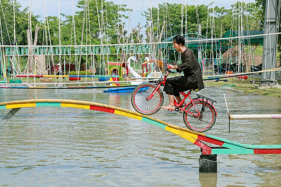 Cycling challenge across a plank bridge at Hoang Hao ecotourism area.