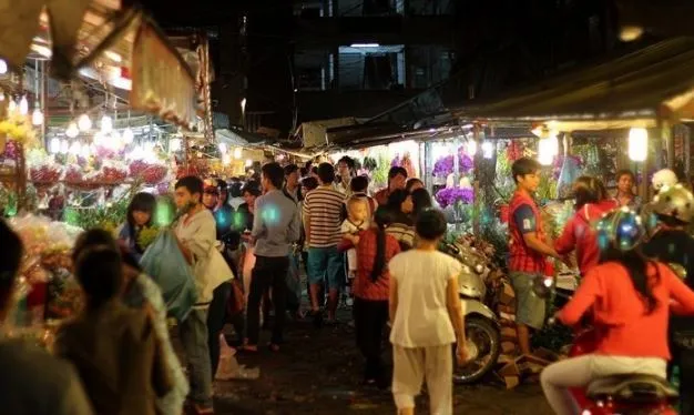 A panoramic view of the bustling Ho Thi Ky Flower Market at night.