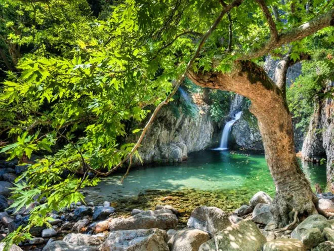 A cascading waterfall in Samothrace surrounded by lush greenery