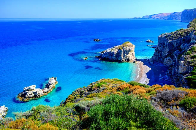 A serene beach in Kythira with clear turquoise water and rocky cliffs