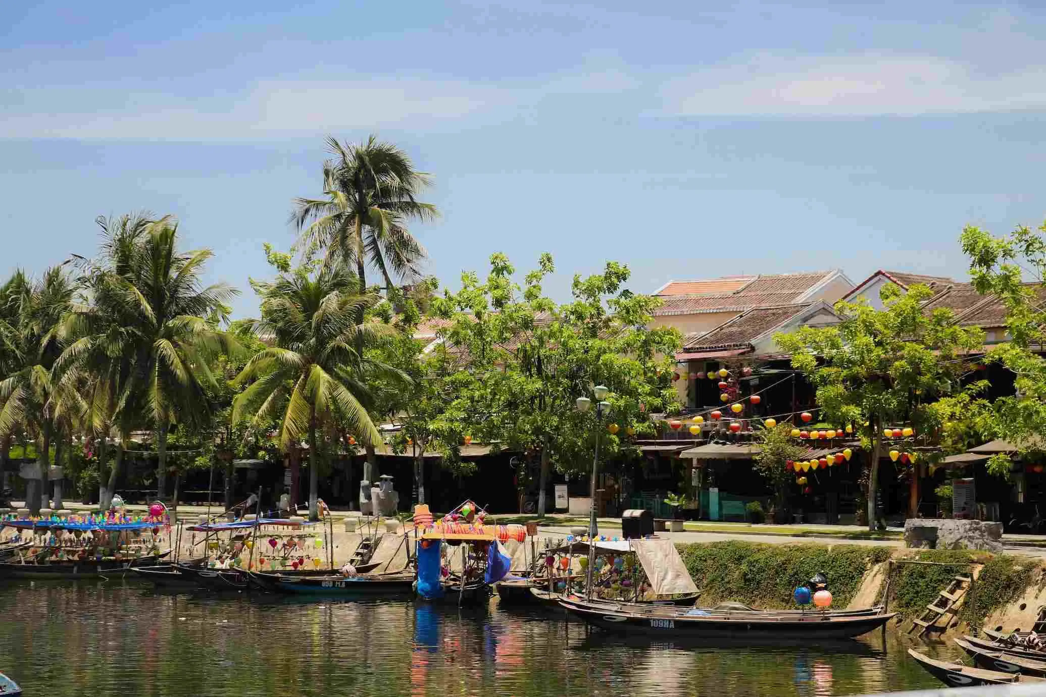 Riverside houses with old architecture line the banks of the Thu Bon River.